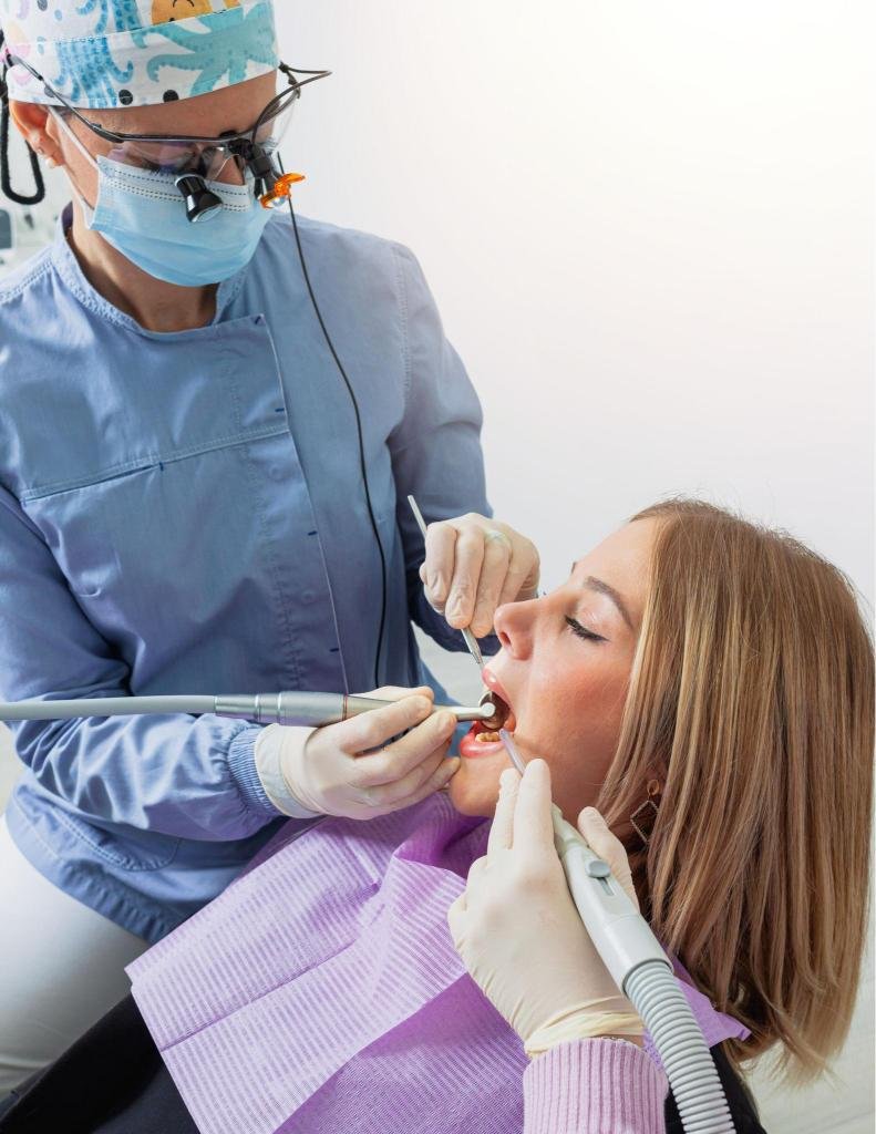 Dentiste réalisant des soins dentaires avec des instruments professionnels sur une patiente dans un cabinet dentaire moderne à Tanger.