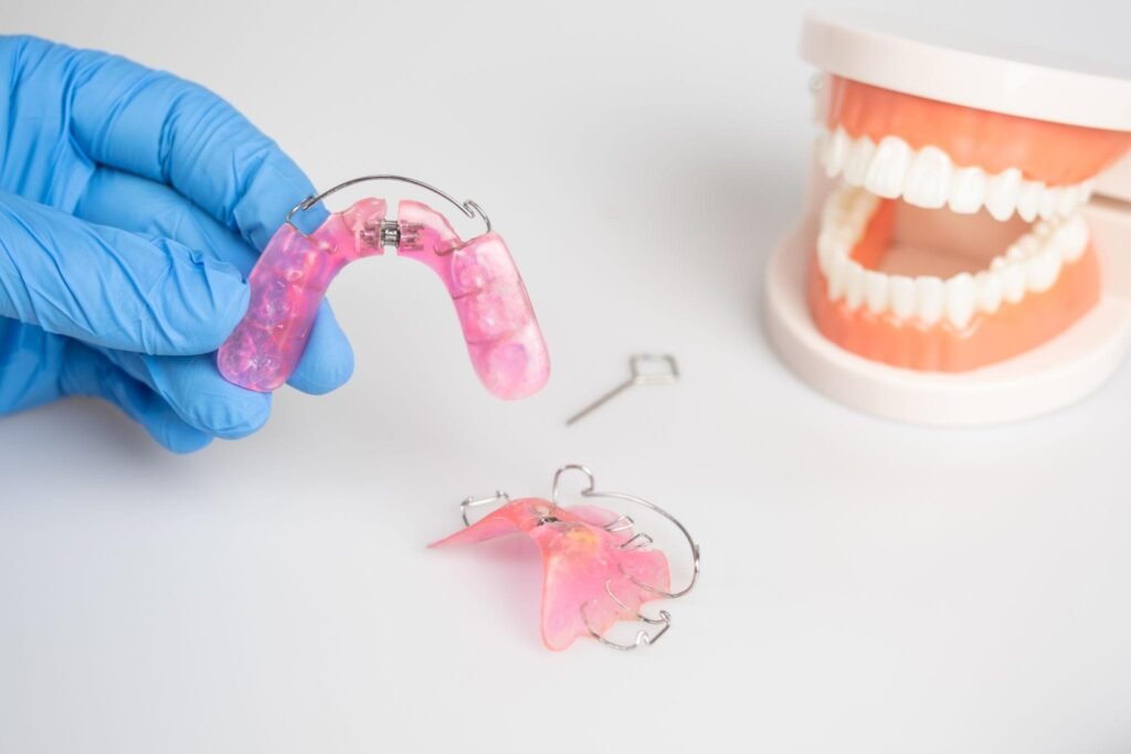 Appareil dentaire adulte amovible présenté par un professionnel de santé, avec appareil orthodontique fonctionnel et modèle de dents utilisé pour le suivi du traitement d’alignement dentaire.