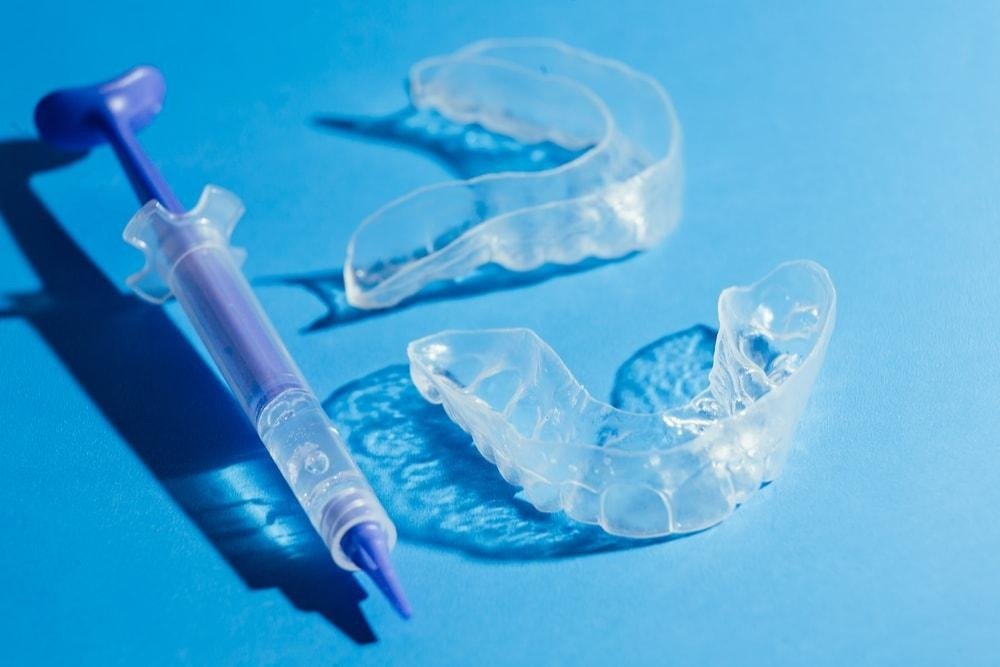 Gouttières transparentes et gel de blanchiment dentaire présentés avant un traitement d’éclaircissement des dents à domicile, avec aligneurs personnalisés et produit de blanchiment professionnel.