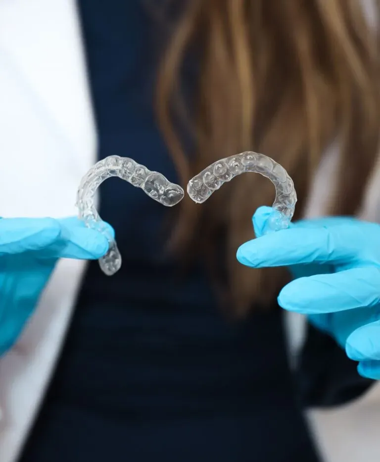 Aligneurs transparents Invisalign tenus par un orthodontiste avec gants médicaux dans une clinique d’orthodontie invisible à Tanger.