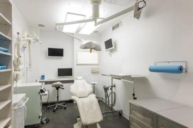 Salle de chirurgie dentaire moderne équipée d’un fauteuil médical, d’éclairages opératoires et d’équipements spécialisés pour les interventions dentaires.