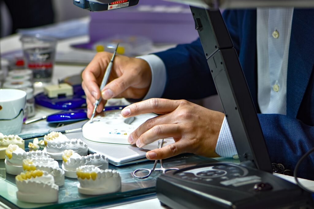 Technicien dentaire travaillant sur des modèles de prothèses dentaires en laboratoire pour la fabrication de restaurations esthétiques et sur implants.