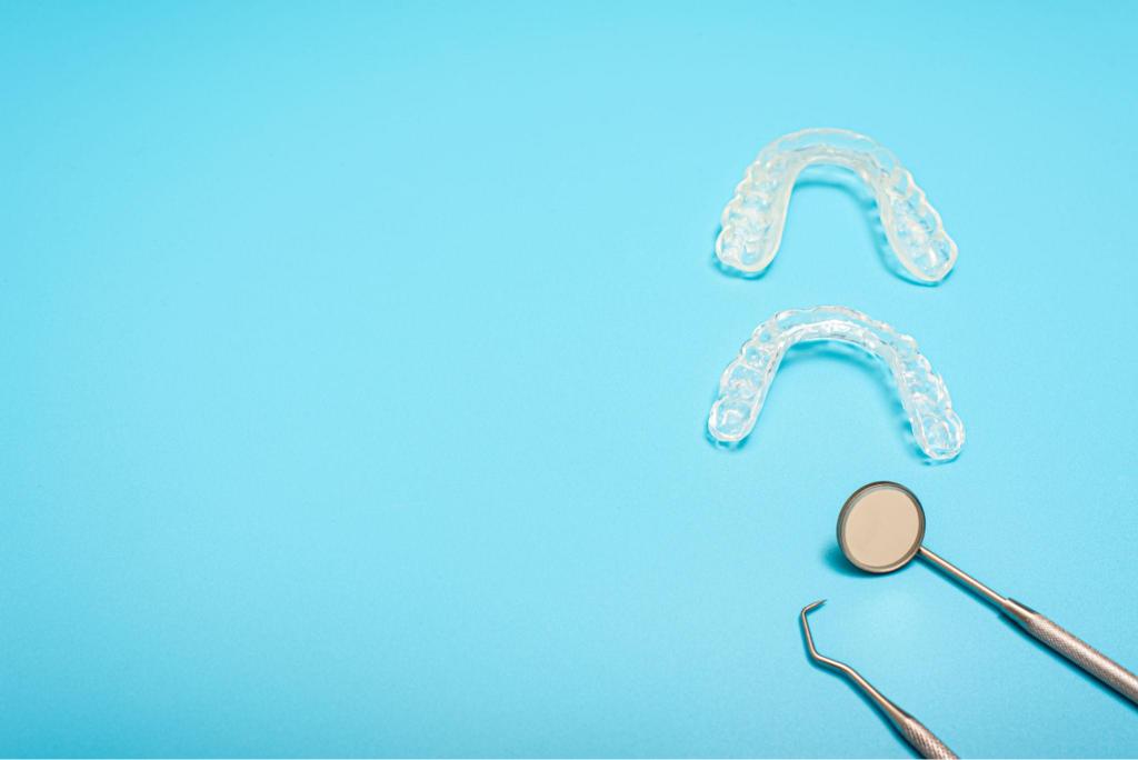 Deux gouttières dentaires transparentes avec miroir et instruments de dentiste sur fond bleu