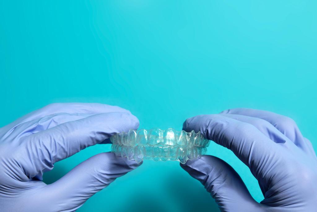 Mains gantées tenant une gouttière dentaire transparente utilisée pour l’alignement des dents