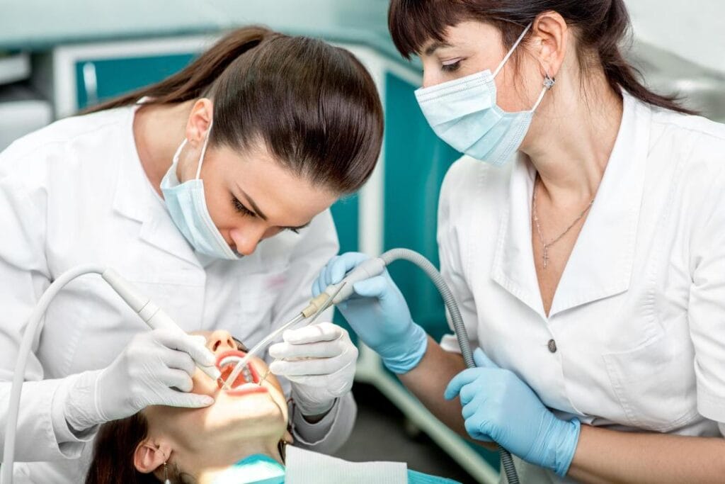 Dentiste et assistante réalisant un soin dentaire à quatre mains
