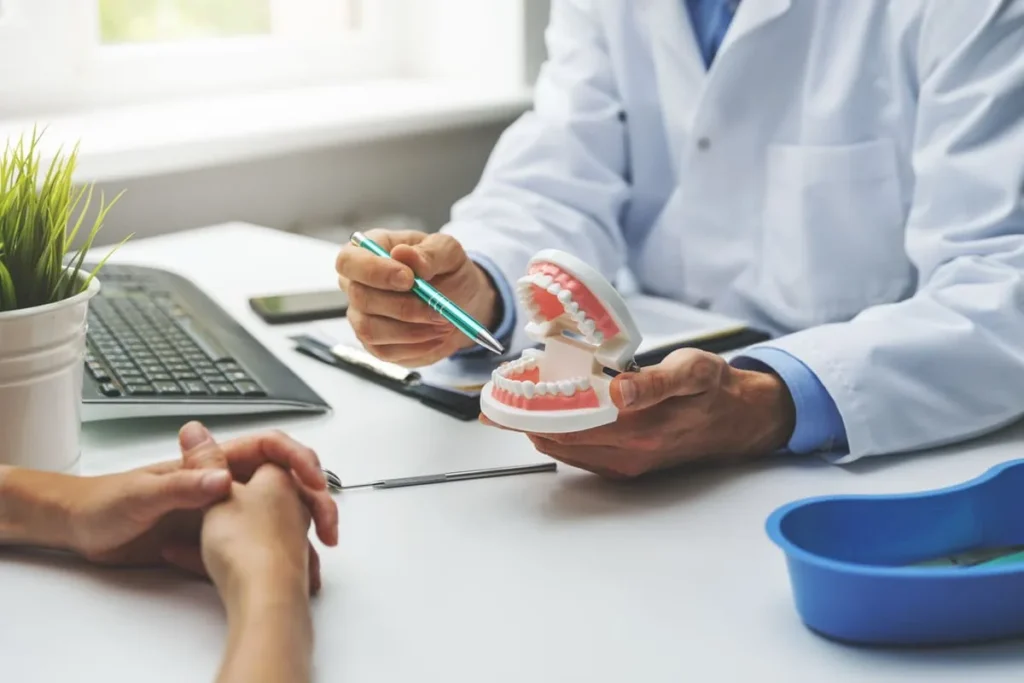 Dentiste expliquant le traitement par aligneurs à une patiente avec un modèle dentaire