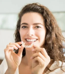 Femme souriante tenant une gouttière dentaire Invisalign