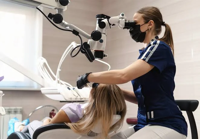 Médecin dentiste effectuant un traitement de précision sous microscope opératoire