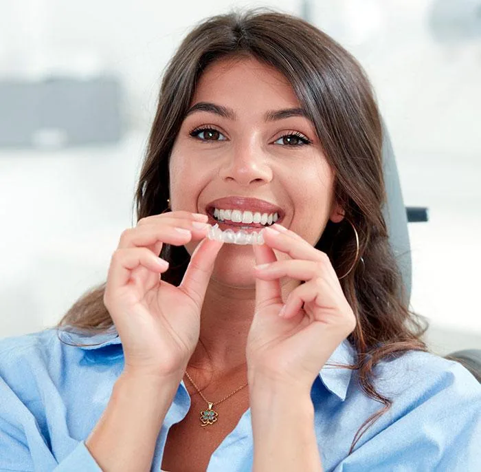 Patiente souriante tenant une gouttière transparente avant un traitement par aligneurs